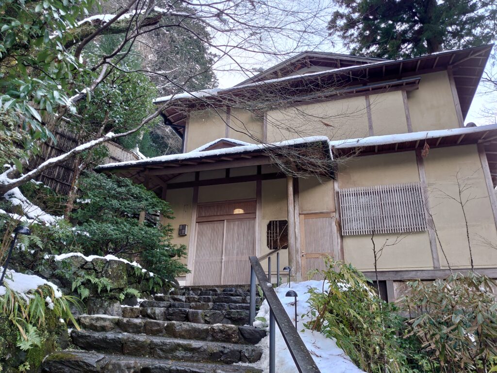 星のや京都の一棟貸し風の建物(谷霞)の外観。苔むした石段と雪景色が調和し、静寂な雰囲気を漂わせている。