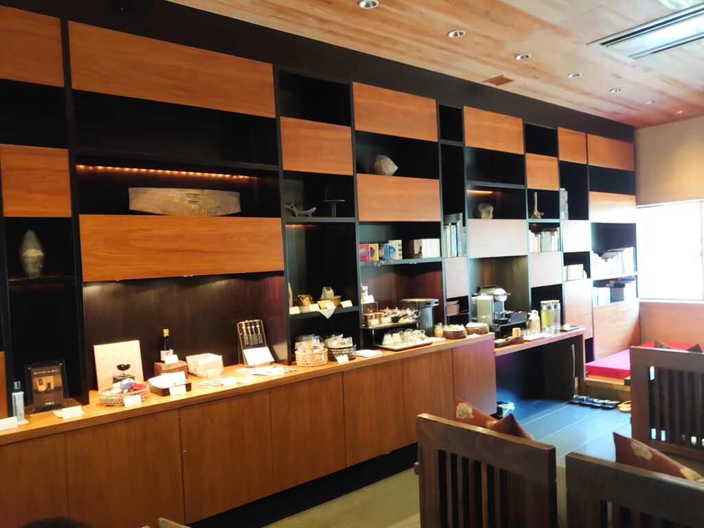 星のや京都のライブラリーラウンジ。木目調の棚に書籍やドリンク類が並び、落ち着いた空間が広がる。