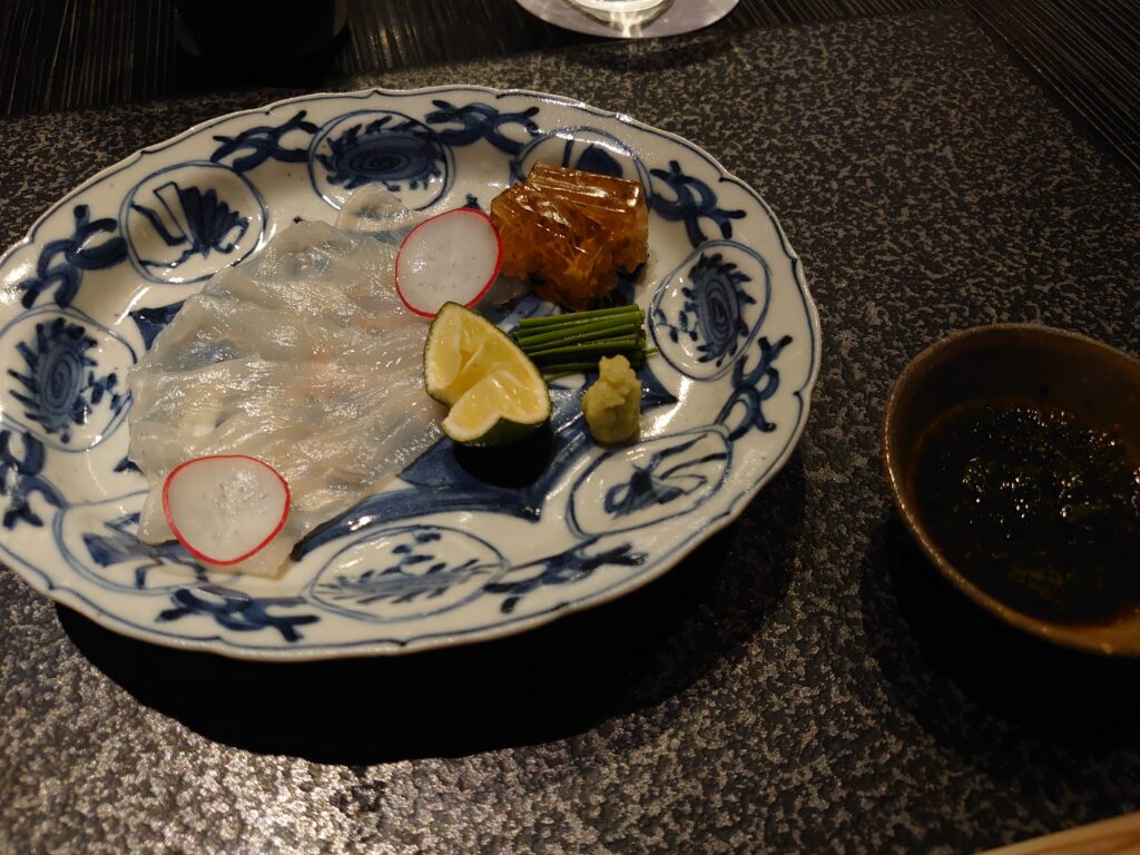 向附はフグの薄造り。美しい青絵の皿にラディッシュやスダチ、薬味とともに盛り付けられている。