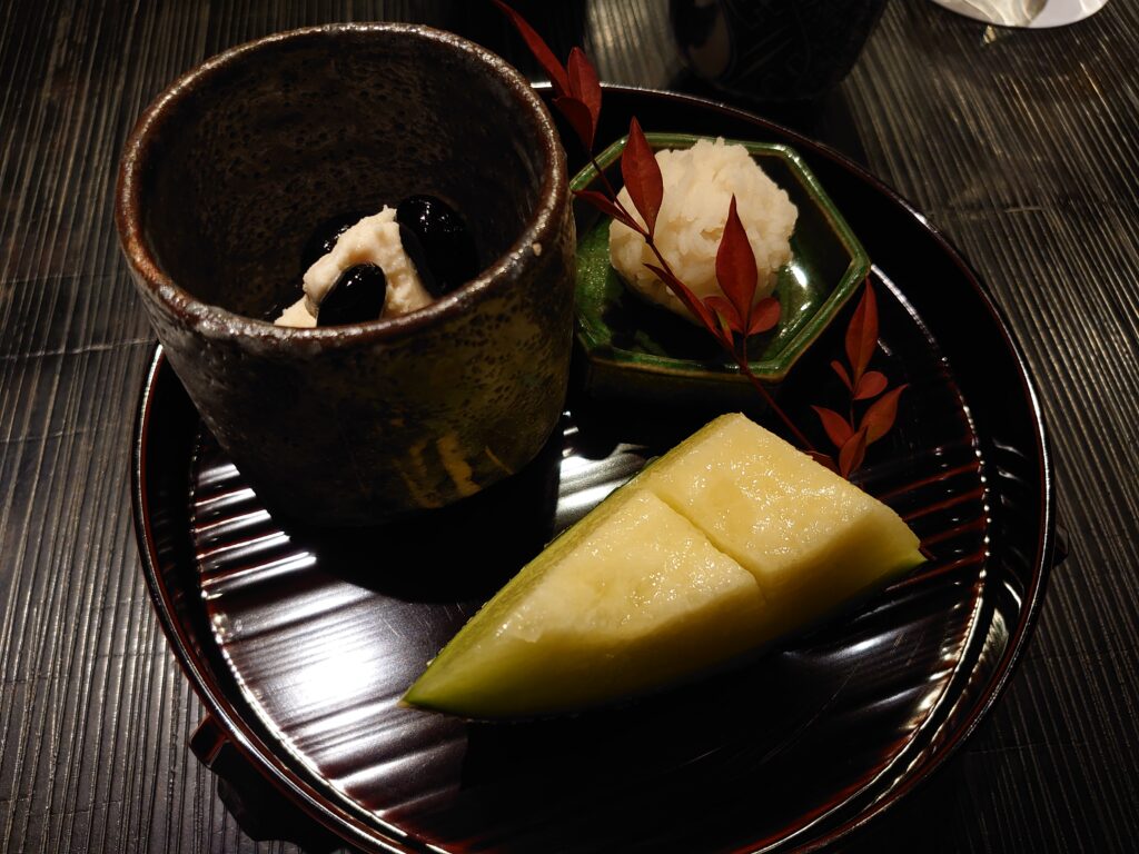 百合根金団、黒豆きな粉アイス、カットメロンの三種盛り。季節感を演出する南天の葉が添えられた、美しい盛り付けのデザート皿。